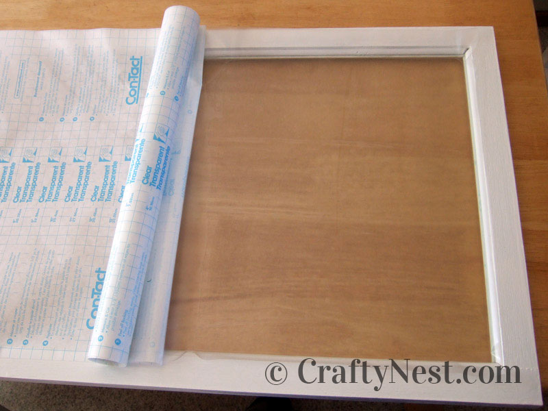 roll-diy-faux-frosted-glass-crafty-nest Applying Con-Tact paper to the glass, photo