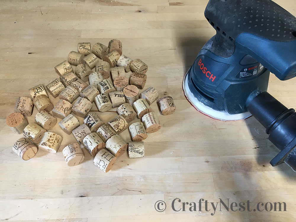 step2-woven-wine-cork-trivet-crafty-nest Sanding the corks with a palm sander, photo